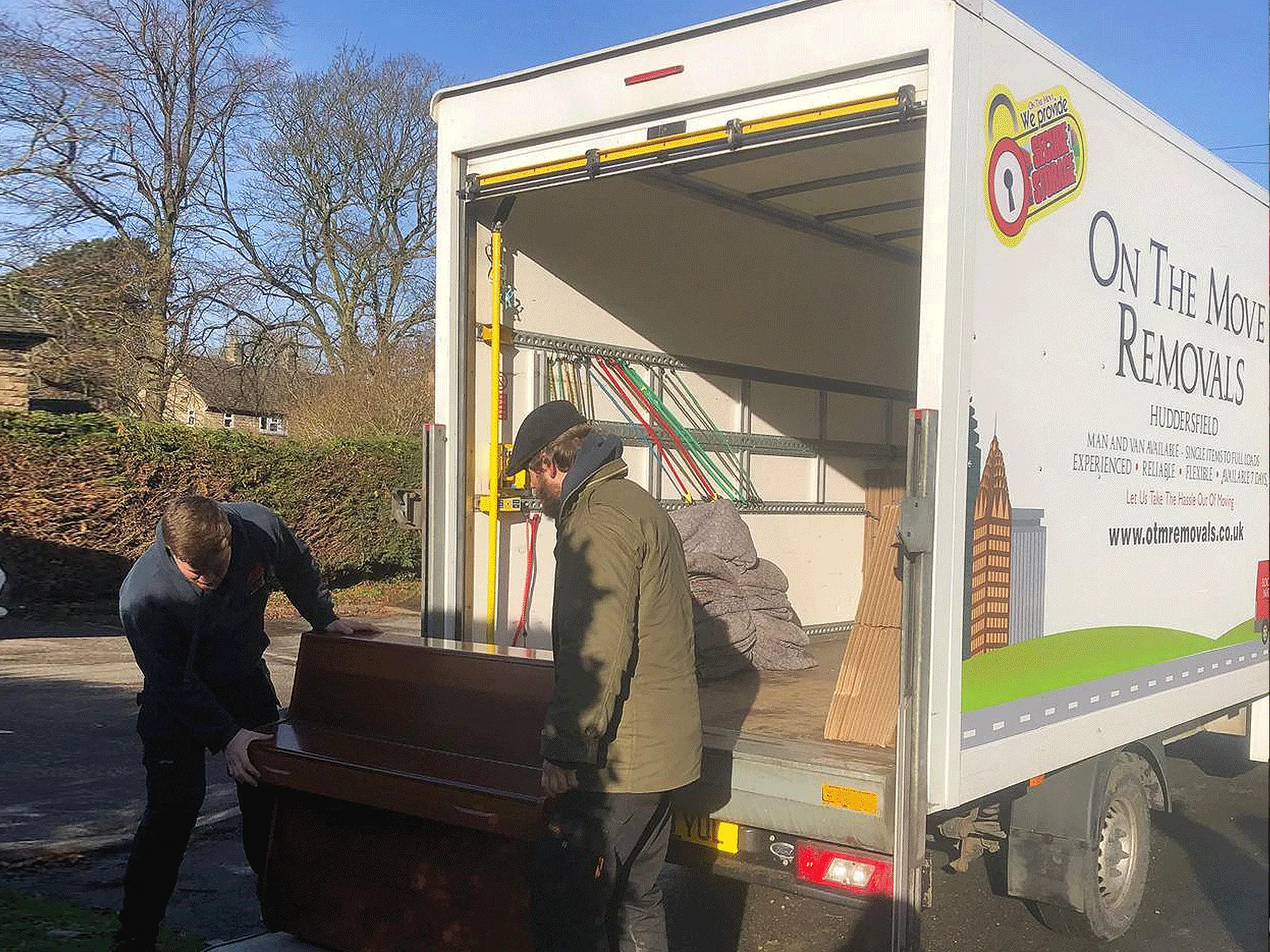 On The Move Removals team handling an upright piano next to the OTM removals van during a Huddersfield piano move