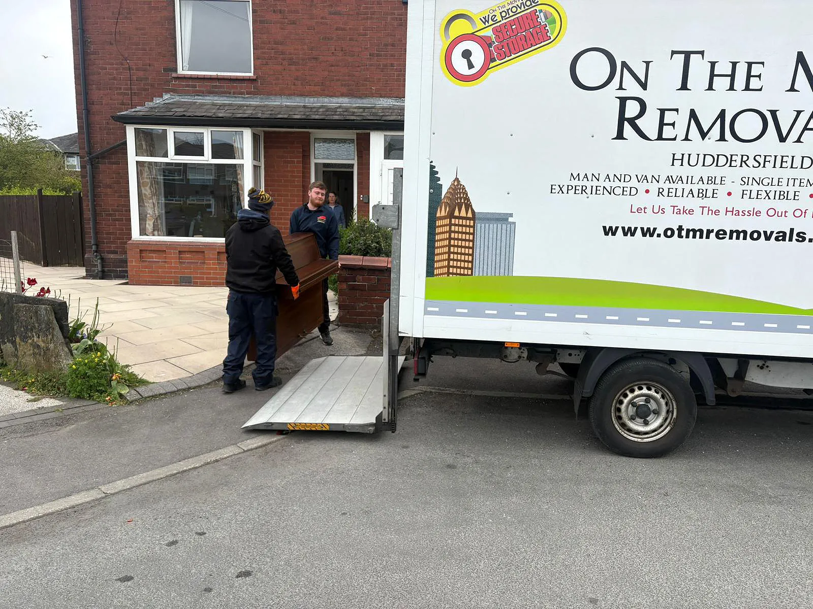 On The Move Removals team loading a wrapped piano up the ramp into a branded OTM van during a Huddersfield piano removal